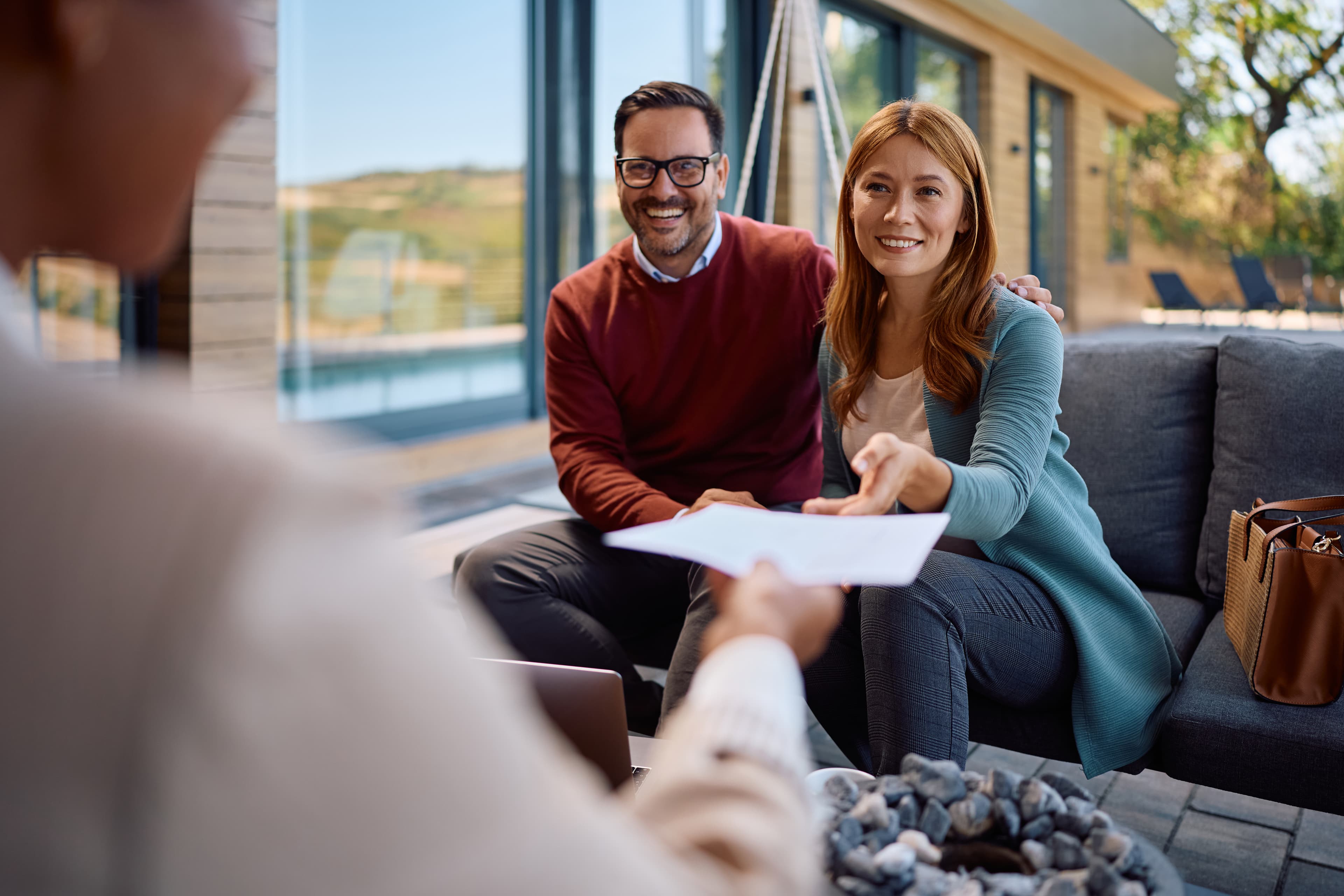 Happy couple reviewing and signing a business contract with a professional