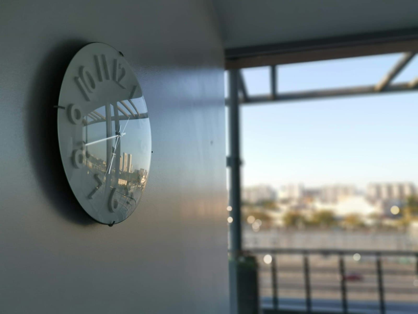 Round wall clock in a bright office beside a window overlooking the city